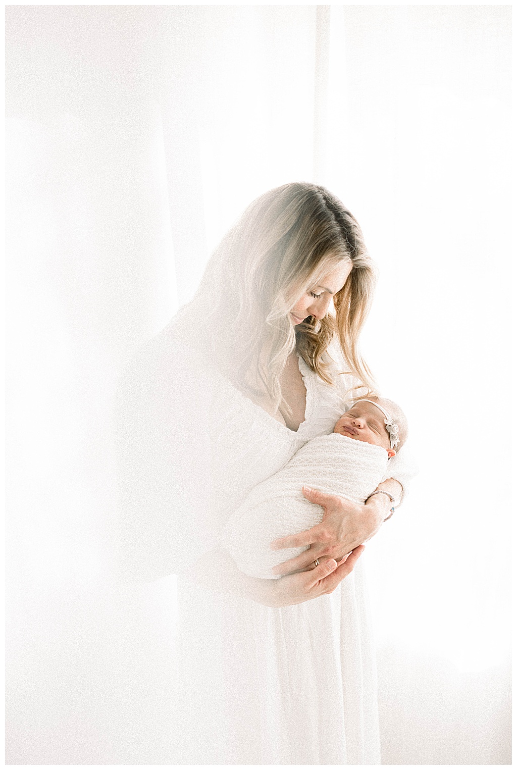 new mom holding newborn for her newborn photoshoot with the studio wardrobe